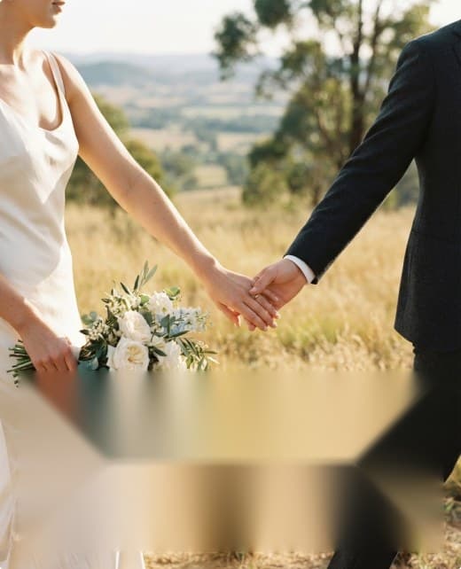 A bride and groom holding hands in a golden field